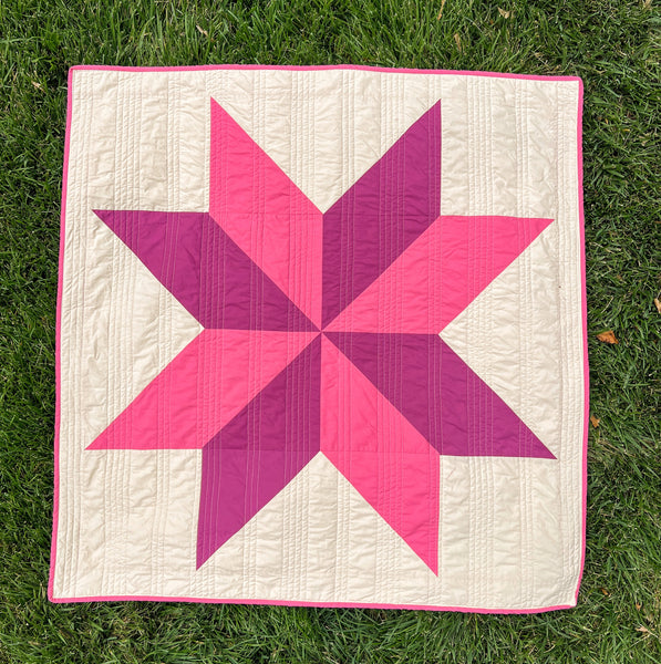 Image of a pink and purple handmade quilt for sale, photographed head on. A wonderful handmade gift for baby or a new mom.