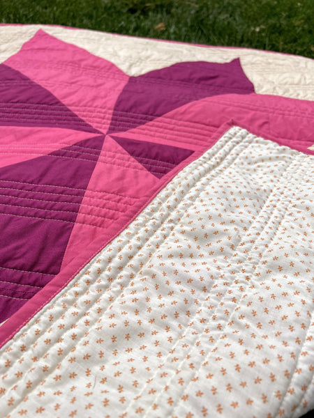 A closeup image of Nemo and Stitch's pink and purple handmade quilt for sale. Photographed up close to see the fabric on the front and back of the quilt. The perfect handmade gift for baby. Celebrate mom with a wonderful handmade gift for her nursery. 