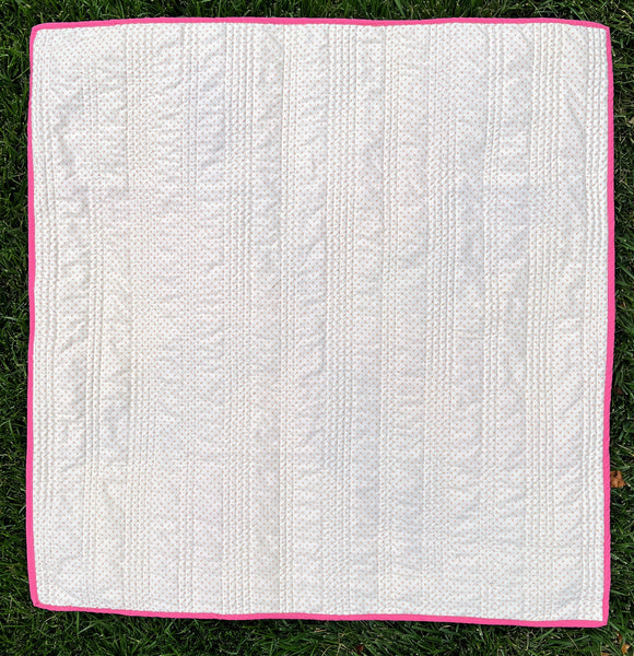 Image of a pink and purple handmade quilt for sale, photographed from the back to show the pattern. A wonderful handmade gift for baby or a new mom.