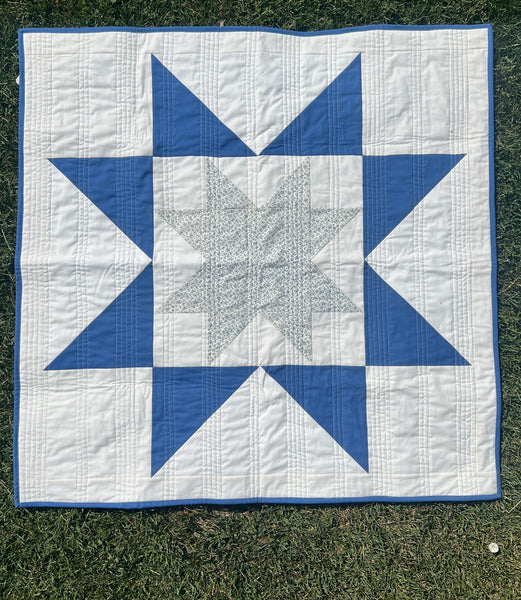 Image of Nemo and Stitch's handmade baby quilt for sale. Blue and white sawtooth star pattern photographed front on with a grass background. quilt for sale. A wonderful baby gift. 